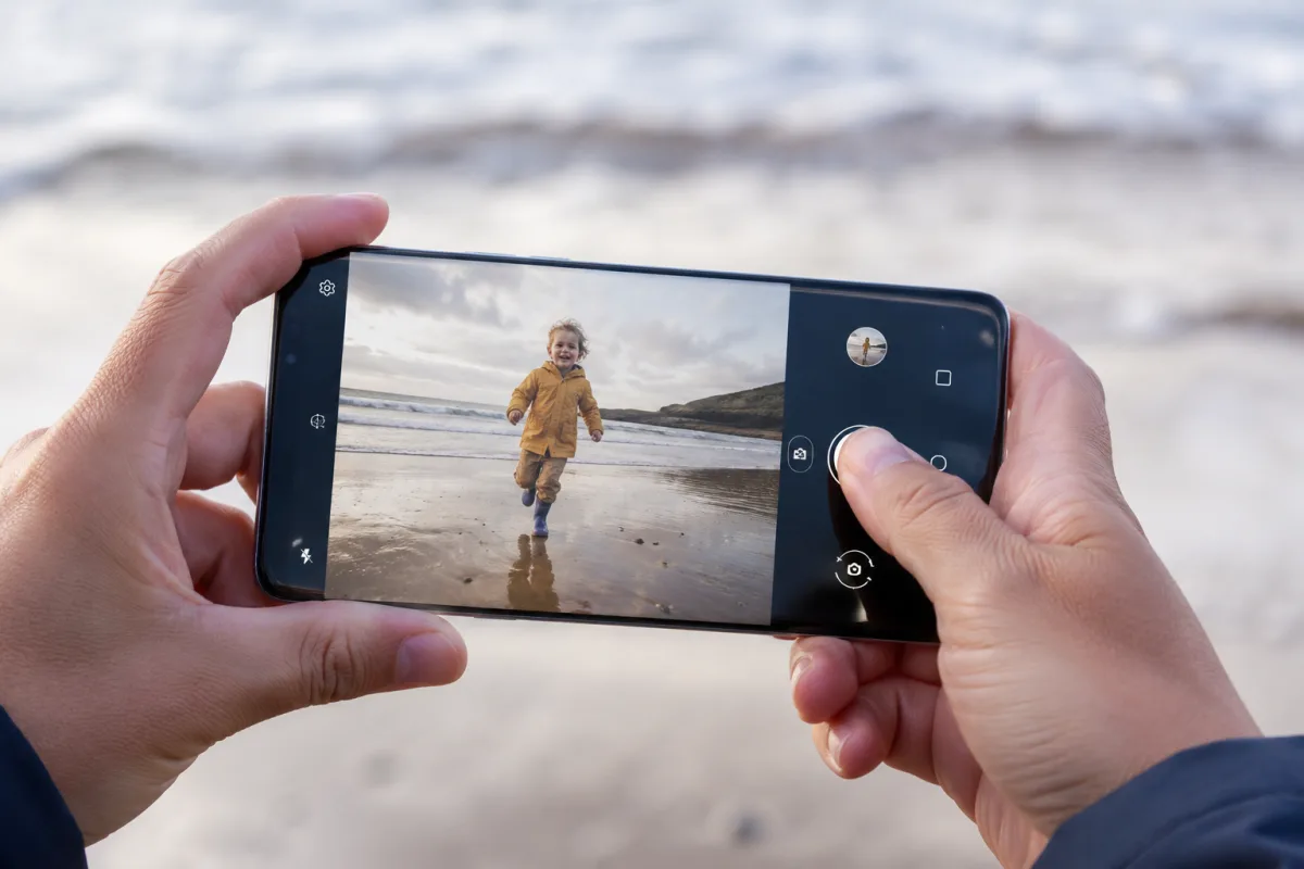 Gros plan sur l'objectif triple capteur d'un smartphone compact posé sur un canapé familial